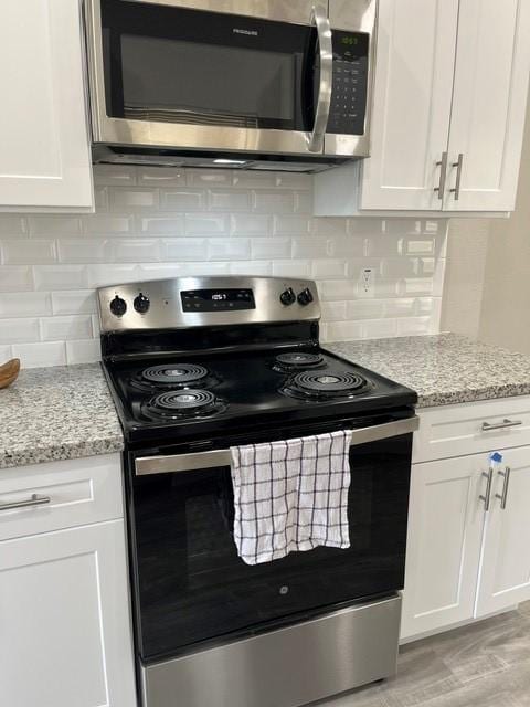 1012 Rd 5606, Cleveland, TX 77327 - kitchen with stainless steel appliances, white cabinets, light stone counters, tasteful backsplash, and light wood-style floors