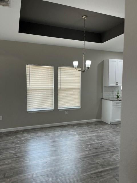 1012 Rd 5606, Cleveland, TX 77327 - unfurnished dining area featuring a chandelier, a raised ceiling, and dark wood-style floors