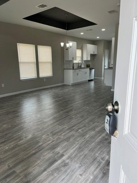 1012 Rd 5606, Cleveland, TX 77327 - unfurnished living room with a chandelier, dark wood-type flooring, healthy amount of natural light, a tray ceiling, and recessed lighting