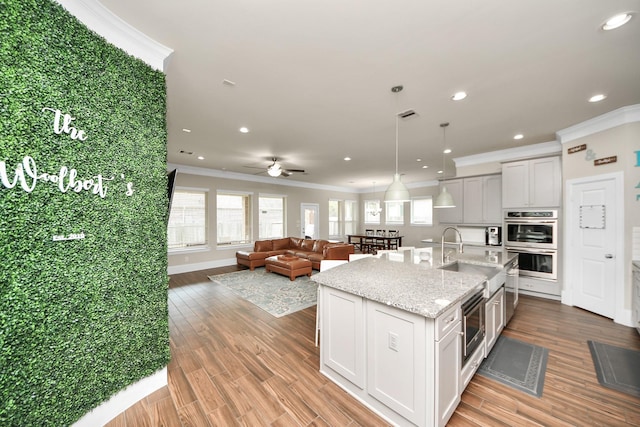 31201 Redwood Manor Ct, Spring, TX 77386 - kitchen with stainless steel appliances, crown molding, a kitchen island with sink, light wood-style floors, and recessed lighting