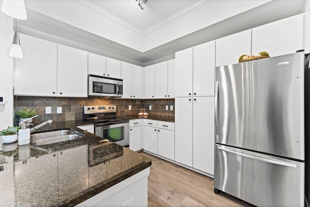 300 St Joseph Pkwy Unit 319, Houston, TX 77002 - kitchen with stainless steel appliances, ornamental molding, light wood-style floors, white cabinets, and decorative backsplash