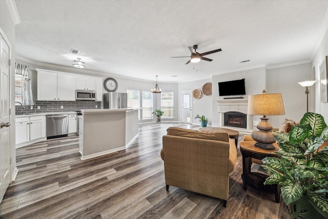 17227 Horsetooth Canyon Dr, Houston, TX 77095 - living room featuring ceiling fan, a fireplace with raised hearth, wood finished floors, ornamental molding, and a chandelier