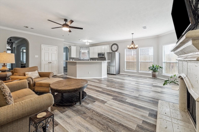 17227 Horsetooth Canyon Dr, Houston, TX 77095 - living room featuring arched walkways, ceiling fan, light wood-type flooring, healthy amount of natural light, and ornamental molding