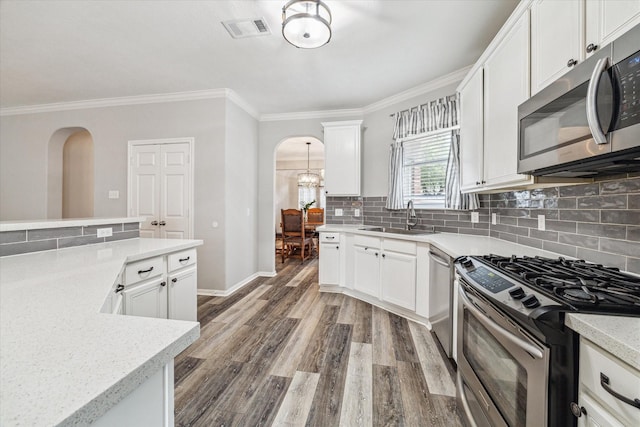 17227 Horsetooth Canyon Dr, Houston, TX 77095 - kitchen with appliances with stainless steel finishes, arched walkways, crown molding, wood finished floors, and white cabinets