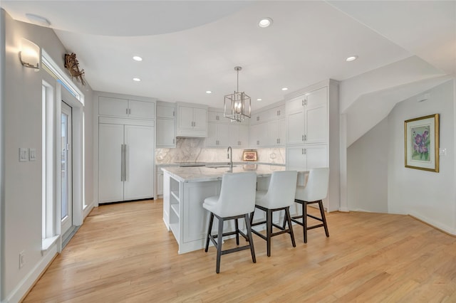 1303 Outrigger, Tiki Island, TX 77554 - kitchen featuring a chandelier, backsplash, light wood-style floors, recessed lighting, and a kitchen breakfast bar