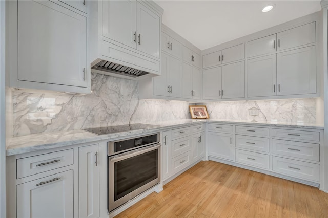 1303 Outrigger, Tiki Island, TX 77554 - kitchen with oven, light stone countertops, recessed lighting, light wood finished floors, and backsplash