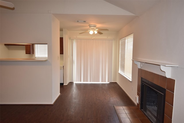 16702 Vista Oak Dr, Houston, TX 77073 - unfurnished living room featuring ceiling fan, a tiled fireplace, dark wood finished floors, and plenty of natural light