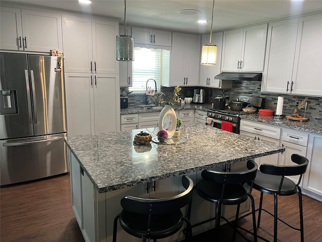 8823 Shadow Crest St, Houston, TX 77074 - kitchen with appliances with stainless steel finishes, dark wood-type flooring, under cabinet range hood, dark stone countertops, and tasteful backsplash