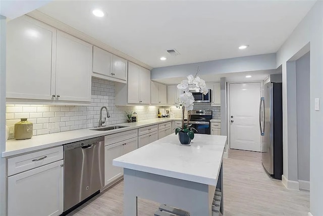 3406 Yoakum Blvd, Houston, TX 77006 - kitchen with stainless steel appliances, decorative backsplash, light countertops, light wood-style floors, and a center island