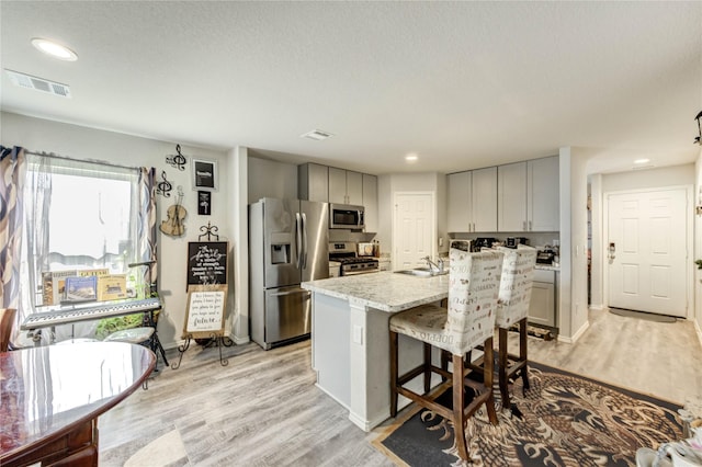 4338 Tulip Oak Dr, Houston, TX 77068 - kitchen featuring stainless steel appliances, a kitchen island with sink, light wood-style flooring, a breakfast bar area, and recessed lighting