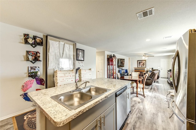 4338 Tulip Oak Dr, Houston, TX 77068 - kitchen featuring stainless steel appliances, light wood-style floors, ceiling fan, light countertops, and an island with sink