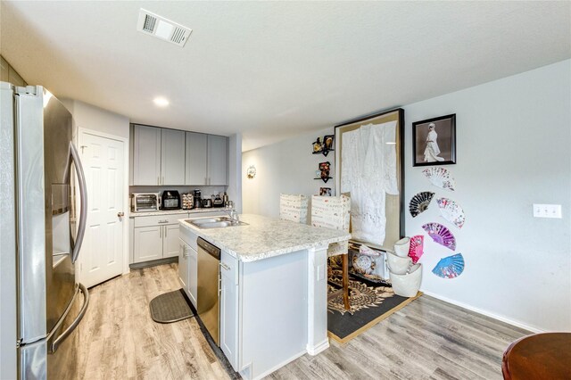4338 Tulip Oak Dr, Houston, TX 77068 - kitchen featuring appliances with stainless steel finishes, light wood finished floors, light countertops, and an island with sink