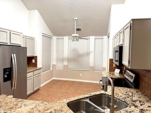 4418 Treasure Trl, Sugar Land, TX 77479 - kitchen with stainless steel appliances, decorative backsplash, a ceiling fan, light tile patterned floors, and vaulted ceiling