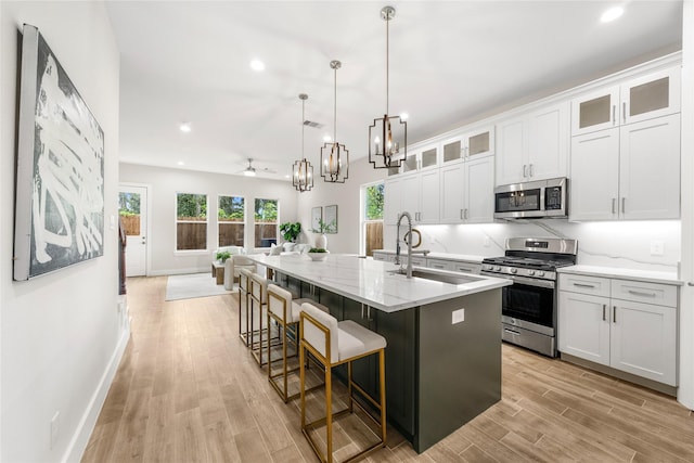6216 Carver Rd, Houston, TX 77091 - kitchen with appliances with stainless steel finishes, light wood-style floors, recessed lighting, open floor plan, and a center island with sink