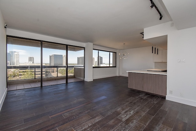 49 Briar Hollow Ln Unit 1106, Houston, TX 77027 - unfurnished living room with a chandelier, dark wood-style floors, rail lighting, and a city view