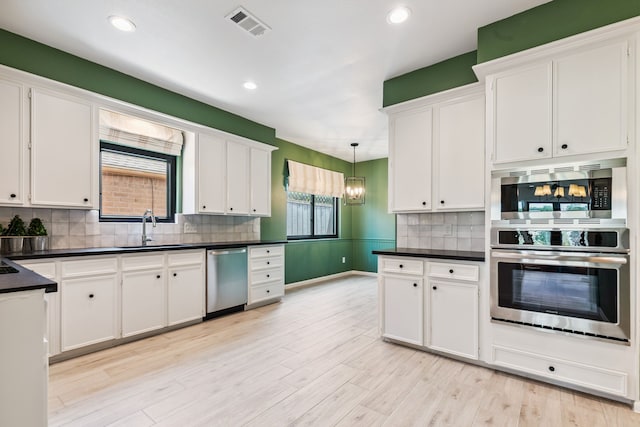 506 Fox Briar Ln, Sugar Land, TX 77478 - kitchen featuring stainless steel appliances, white cabinetry, dark countertops, light wood-style flooring, and decorative backsplash