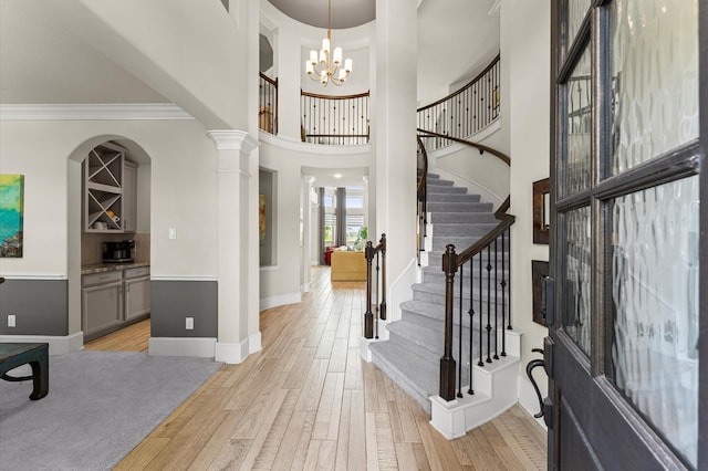 32647 Turning Springs Dr, Fulshear, TX 77423 - entryway featuring light wood-style flooring, stairs, ornamental molding, a chandelier, and a towering ceiling