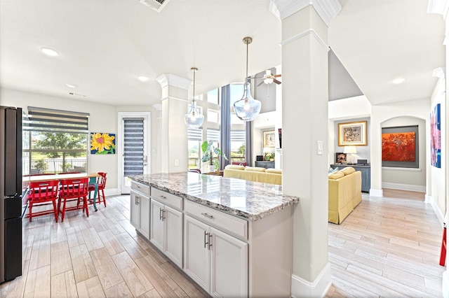 32647 Turning Springs Dr, Fulshear, TX 77423 - kitchen with freestanding refrigerator, ornate columns, light wood-style floors, light stone countertops, and recessed lighting