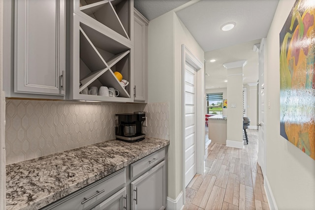 32647 Turning Springs Dr, Fulshear, TX 77423 - bar featuring decorative backsplash, light wood-style flooring, and decorative columns