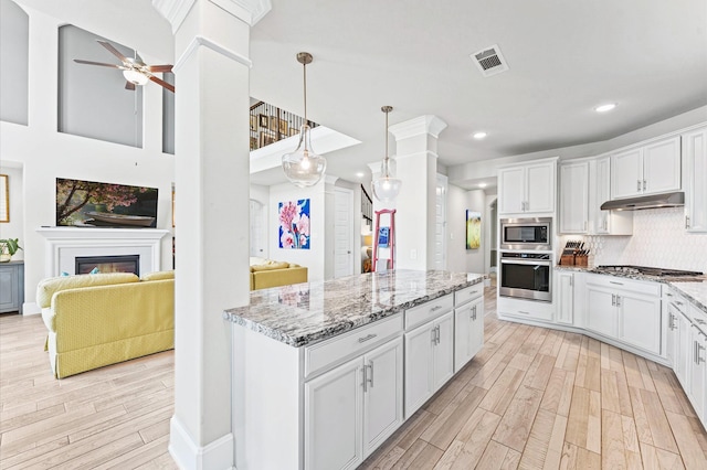 32647 Turning Springs Dr, Fulshear, TX 77423 - kitchen with stainless steel appliances, under cabinet range hood, light wood-type flooring, ceiling fan, and white cabinetry