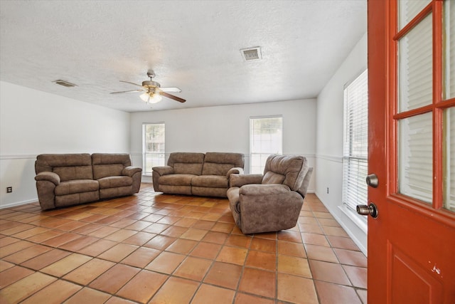 11937 Lakewood W Dr, Cypress, TX 77429 - living room featuring light tile patterned floors, ceiling fan, healthy amount of natural light, and a textured ceiling