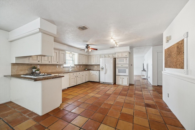 11937 Lakewood W Dr, Cypress, TX 77429 - kitchen with white appliances, decorative backsplash, a peninsula, ceiling fan, and a textured ceiling