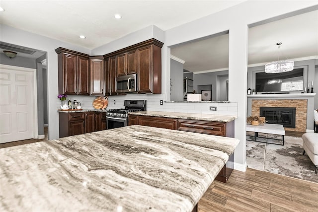 5403 Winlock Trace Ct, Katy, TX 77450 - kitchen featuring appliances with stainless steel finishes, wood finished floors, dark brown cabinetry, light stone counters, and decorative backsplash