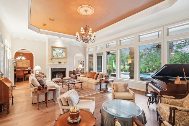 6230 Pebble Beach Dr, Houston, TX 77069 - living room featuring a chandelier, a raised ceiling, light wood-style flooring, ornamental molding, and a fireplace