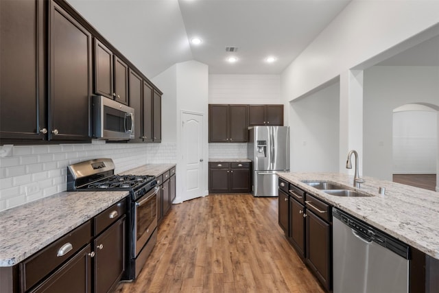 20123 Cascading Falls Blvd, Cypress, TX 77433 - kitchen with stainless steel appliances, arched walkways, dark brown cabinets, decorative backsplash, and light stone countertops