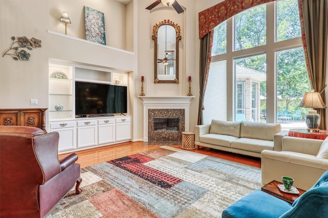 22806 Rachels Manor Dr, Katy, TX 77494 - living area featuring ceiling fan, a high ceiling, a fireplace, built in shelves, and light wood finished floors