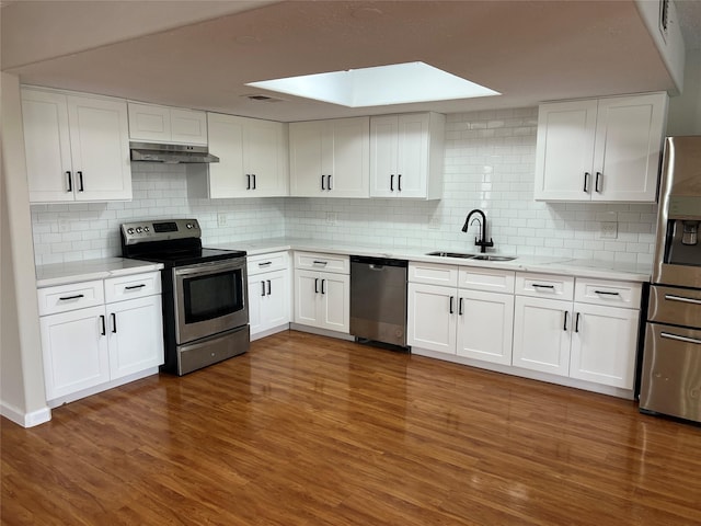 10719 Bellfair Dr, Houston, TX 77072 - kitchen featuring stainless steel appliances, under cabinet range hood, wood finished floors, decorative backsplash, and white cabinetry