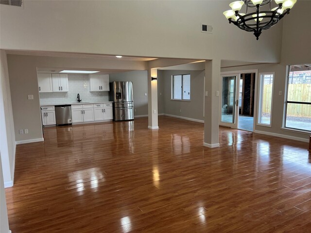 10719 Bellfair Dr, Houston, TX 77072 - unfurnished living room featuring a chandelier, dark wood finished floors, a towering ceiling, and plenty of natural light
