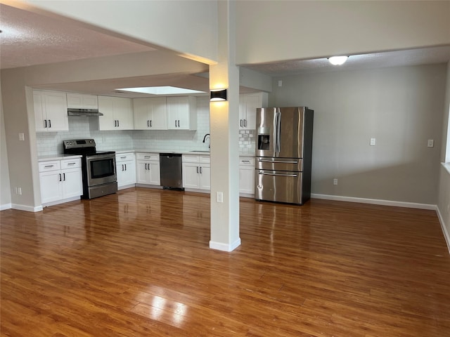 10719 Bellfair Dr, Houston, TX 77072 - kitchen with appliances with stainless steel finishes, decorative backsplash, under cabinet range hood, light countertops, and white cabinetry