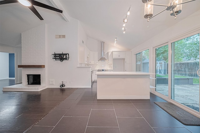 3407 Hillstone Dr, Sugar Land, TX 77479 - kitchen with wall chimney exhaust hood, white cabinets, a center island, tasteful backsplash, and a brick fireplace