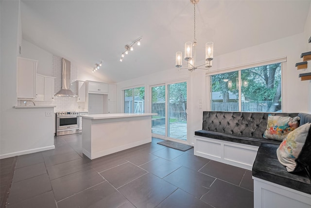 3407 Hillstone Dr, Sugar Land, TX 77479 - kitchen with stainless steel range with electric stovetop, vaulted ceiling, backsplash, white cabinetry, and wall chimney exhaust hood