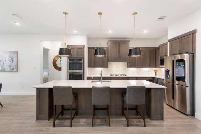 11111 Heartleaf Aster Way, Cypress, TX 77433 - kitchen with stainless steel appliances, dark brown cabinets, light wood finished floors, tasteful backsplash, and light countertops