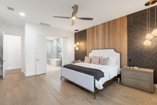 11111 Heartleaf Aster Way, Cypress, TX 77433 - bedroom featuring light wood-style floors, ensuite bath, ceiling fan, and an accent wall