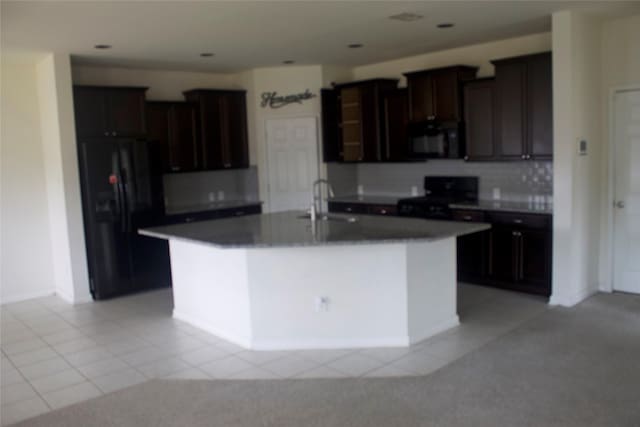 26350 Riley Glen Dr, Richmond, TX 77406 - kitchen with black appliances, a kitchen island with sink, light tile patterned flooring, dark brown cabinets, and recessed lighting