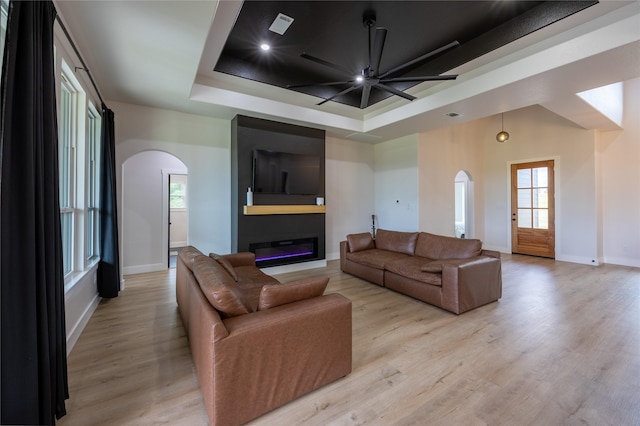 1000 Denson Allen Rd, Coldspring, TX 77331 - living room with arched walkways, a raised ceiling, a ceiling fan, light wood-style flooring, and a large fireplace