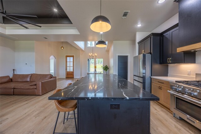 1000 Denson Allen Rd, Coldspring, TX 77331 - kitchen featuring appliances with stainless steel finishes, light wood-style flooring, range hood, open floor plan, and a chandelier