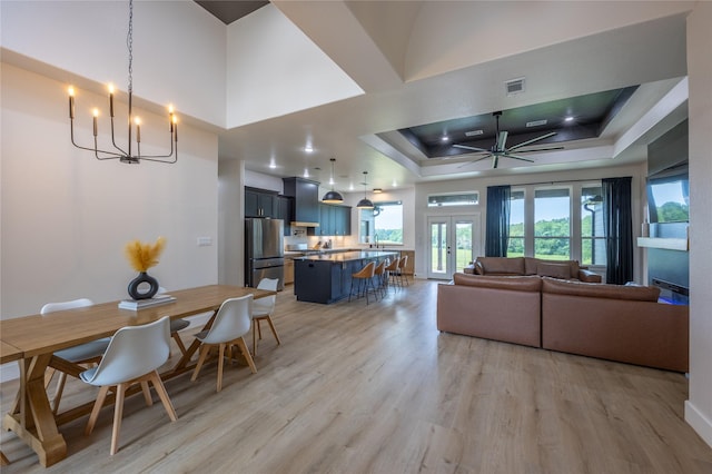 1000 Denson Allen Rd, Coldspring, TX 77331 - dining space featuring a raised ceiling, light wood finished floors, a chandelier, ceiling fan, and french doors