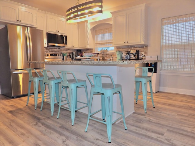 110 Pelican Pl, Surfside Beach, TX 77541 - kitchen with stainless steel appliances, light wood-style floors, white cabinetry, and tasteful backsplash