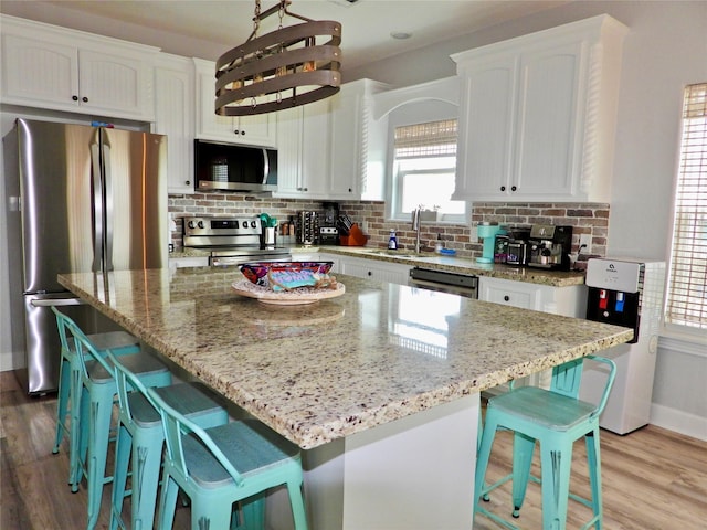 110 Pelican Pl, Surfside Beach, TX 77541 - kitchen with appliances with stainless steel finishes, white cabinets, light wood-style floors, and tasteful backsplash