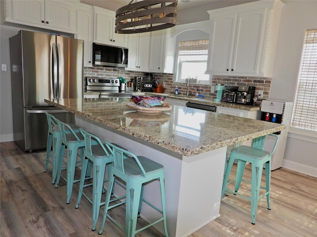 110 Pelican Pl, Surfside Beach, TX 77541 - kitchen featuring appliances with stainless steel finishes, white cabinets, light wood-type flooring, and tasteful backsplash