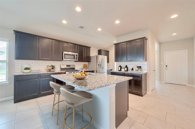 3227 Zephyr Park Ln, Katy, TX 77494 - kitchen with stainless steel appliances, tasteful backsplash, a kitchen island with sink, light tile patterned floors, and recessed lighting