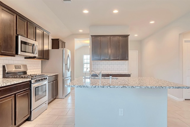 3227 Zephyr Park Ln, Katy, TX 77494 - kitchen with appliances with stainless steel finishes, recessed lighting, dark brown cabinets, light tile patterned floors, and light stone counters