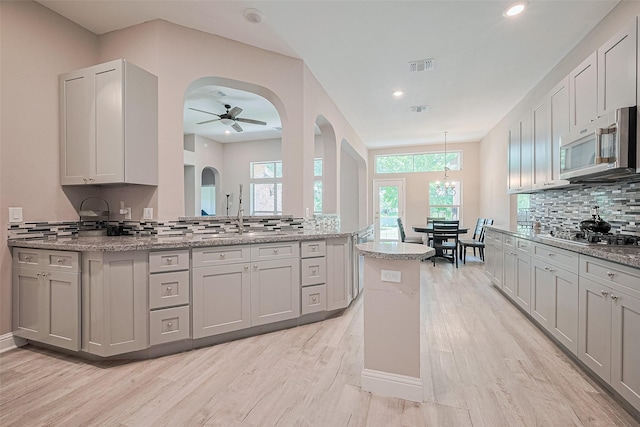 6507 Pinewood Trace Ln, Houston, TX 77041 - kitchen with stainless steel appliances, tasteful backsplash, light wood-type flooring, ceiling fan, and arched walkways