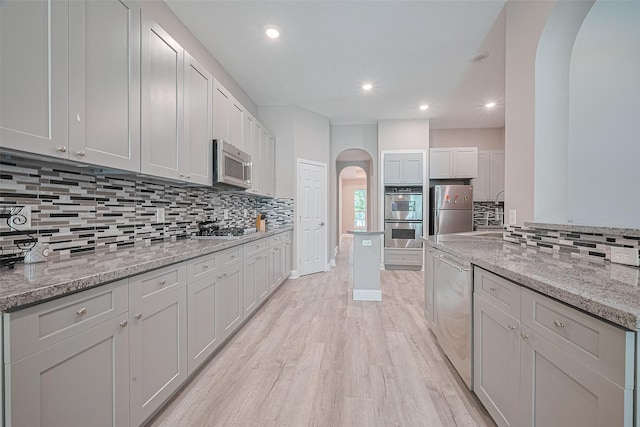 6507 Pinewood Trace Ln, Houston, TX 77041 - kitchen featuring arched walkways, appliances with stainless steel finishes, decorative backsplash, light wood-style flooring, and recessed lighting