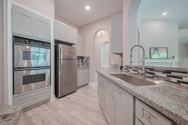 6507 Pinewood Trace Ln, Houston, TX 77041 - kitchen featuring stainless steel appliances, arched walkways, backsplash, light wood-style floors, and recessed lighting
