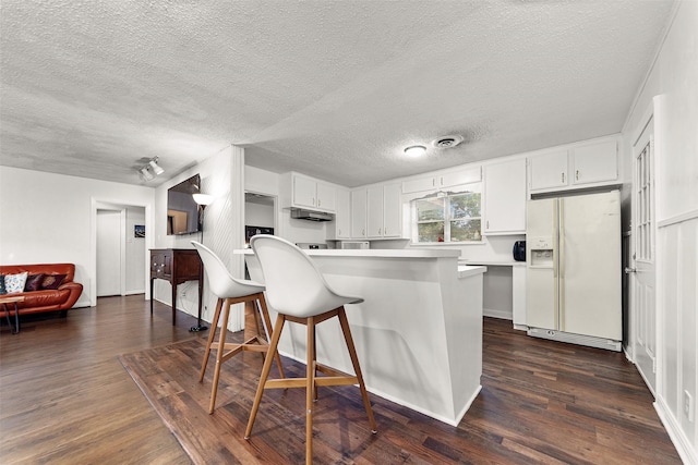 2801 John St, La Marque, TX 77568 - kitchen with white fridge with ice dispenser, a textured ceiling, dark wood-style flooring, a kitchen bar, and white cabinets
